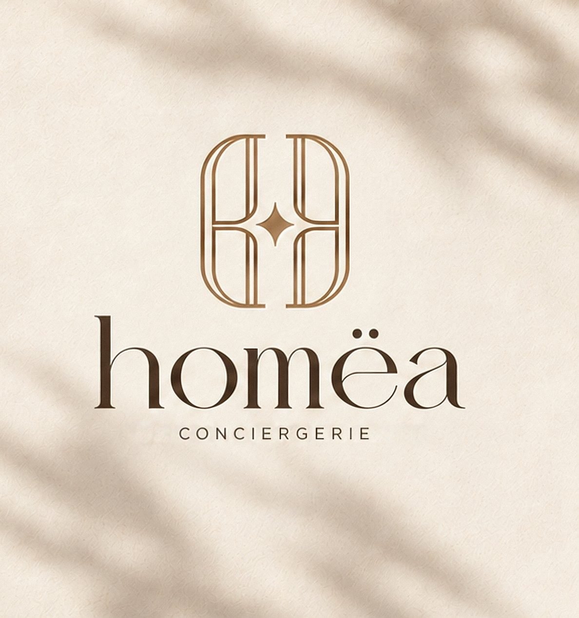 Logo HOMËA sur papier, ombres de feuillage