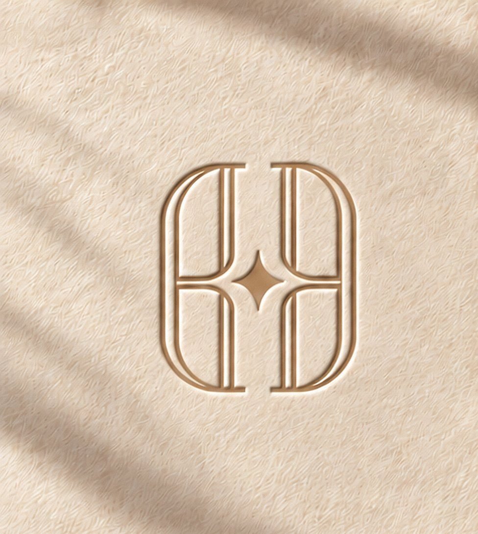 Monogramme HOMËA gaufré sur papier, dans une lumière douce
